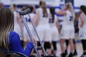 athlete with crutches watching team