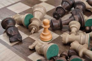 fallen chess pieces surounding an upright chess pawn