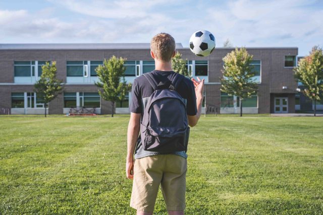 Teenager tossing a soccer ball up in the air