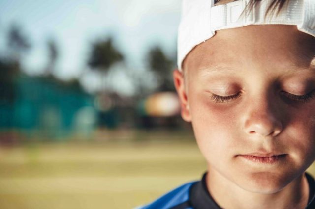 small boy with eyes closed outside