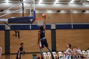 back of basketball player about to dunk the ball in the basket.