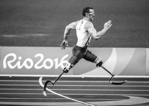 Man with two prosthetic legs running on a track with Rio2016 written on the photo.