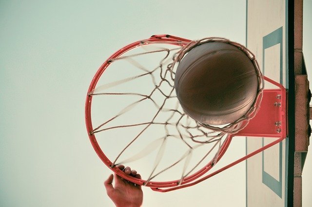 Looking up at hand on basketball rim, ball dropping through the net