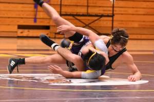 two men wrestling on a mat in a gym