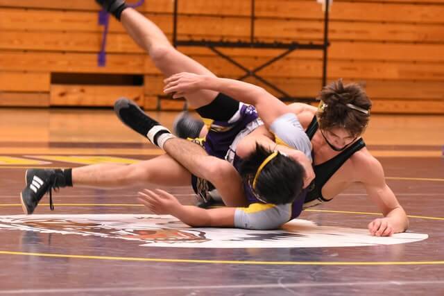 two men wrestling on a mat in a gym