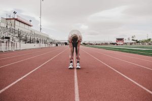 Facing an athlete bent over at the waist looking down in the middle of a track.
