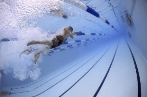 man swimming in lanes seen from behind him underwater