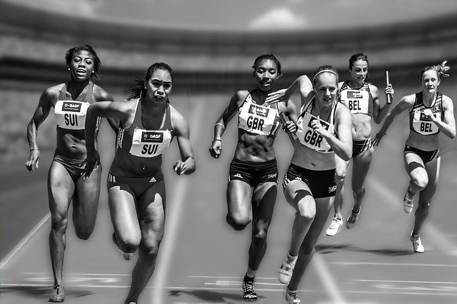 Black and white photo from in front of women racing on a track.