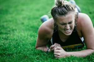 Girl laying on grass with a grimacing expression