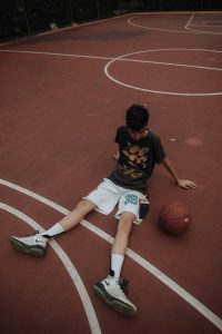 boy sitting on basketball court with ball next to him