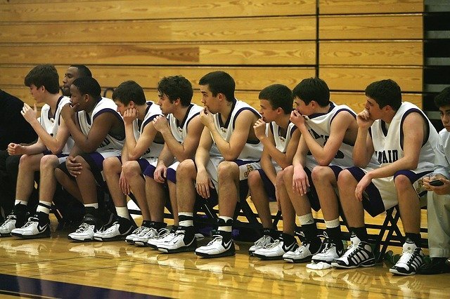 men's basketball team on bench all looking to their right