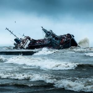 A ship that is sideways looks like it is about to capsize on turbulent waters.