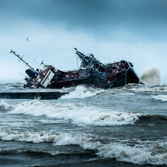 A ship that is sideways looks like it is about to capsize on turbulent waters.