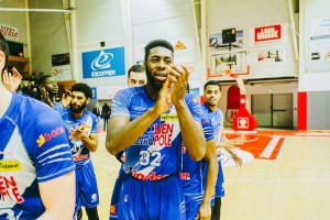 Several basketball players in blue uniforms on a court clapping their hands.