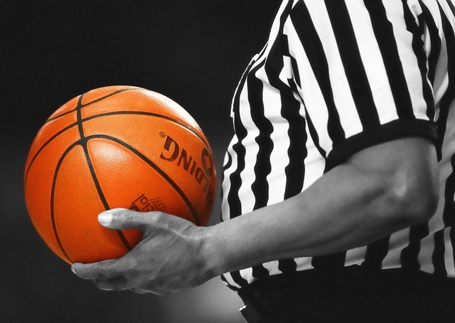The midriff of a basketball referee holding a basketball