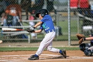 young boy swinging the bat at home base