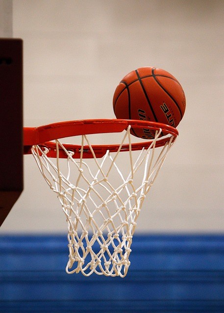 Basketball on the rim about to drop into the net