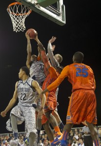 basketball players under a basket, one player is raising the ball.