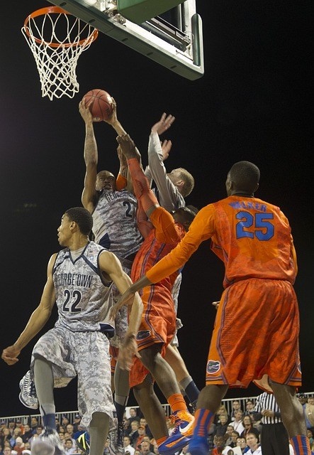 basketball players under a basket, one player is raising the ball.
