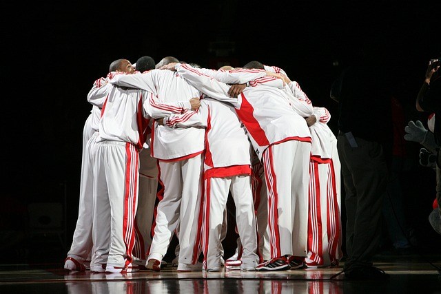 team huddled with heads bowed wearing team sweats