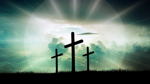 sun shining behind three crosses