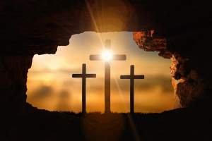 sun shining from behind three crosses