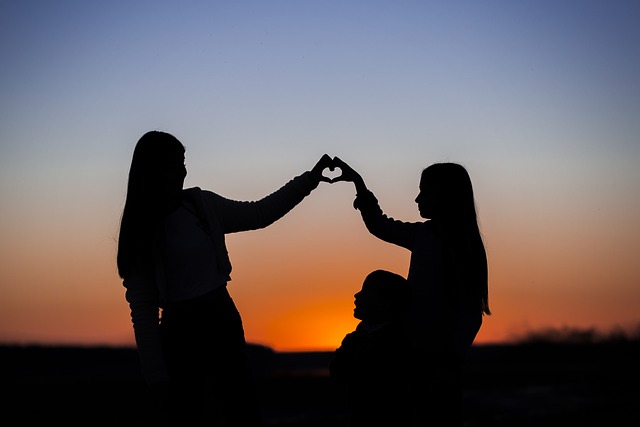 Silhouette of two girls making a heart with their hands