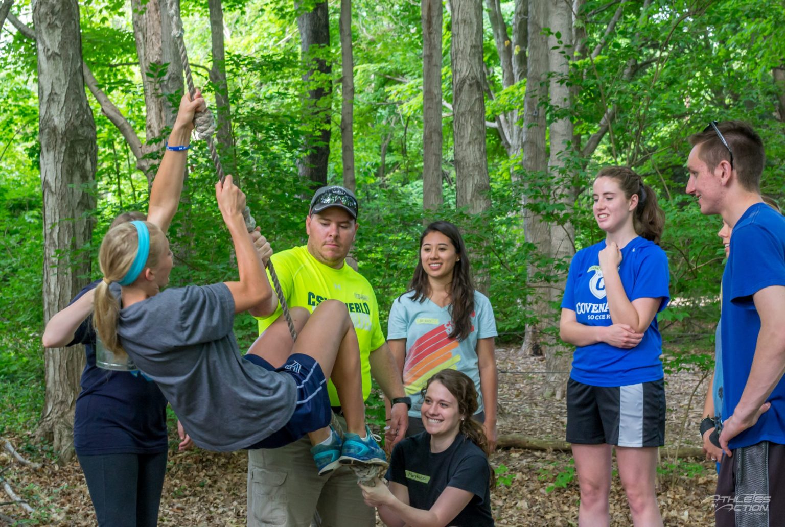 High school athletes lifting a teammate during a team-building activity in the woods