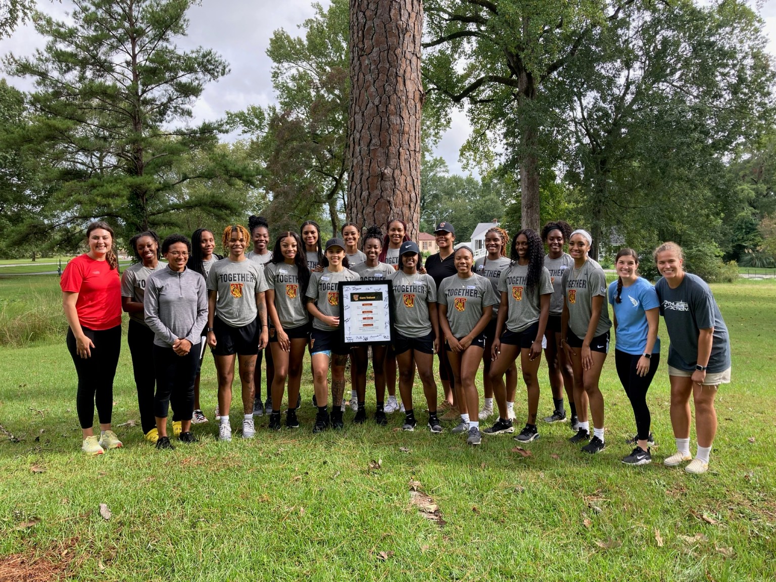 College team gathered outdoors with their retreat plaque
