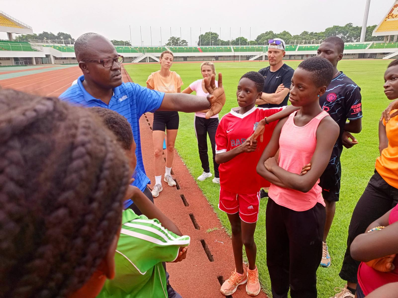 An AIA coach leading a group of young track athletes in Togo