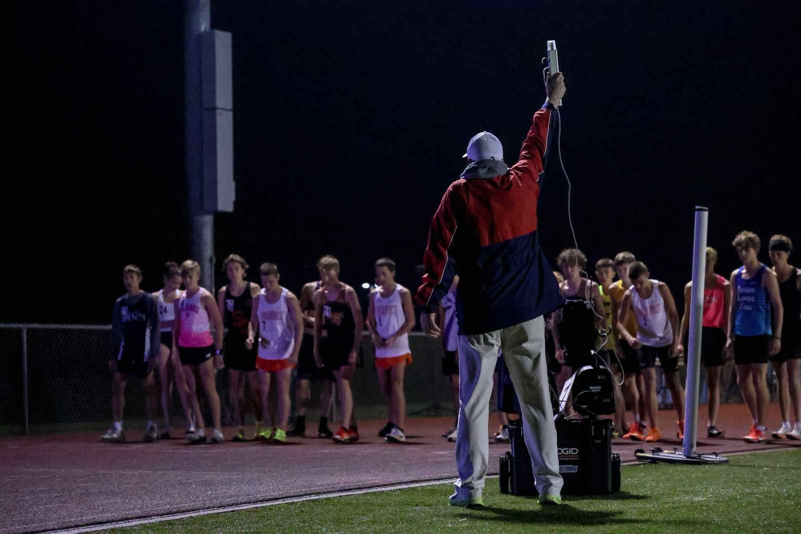 Runners on the track at night at the Evening of Miles race