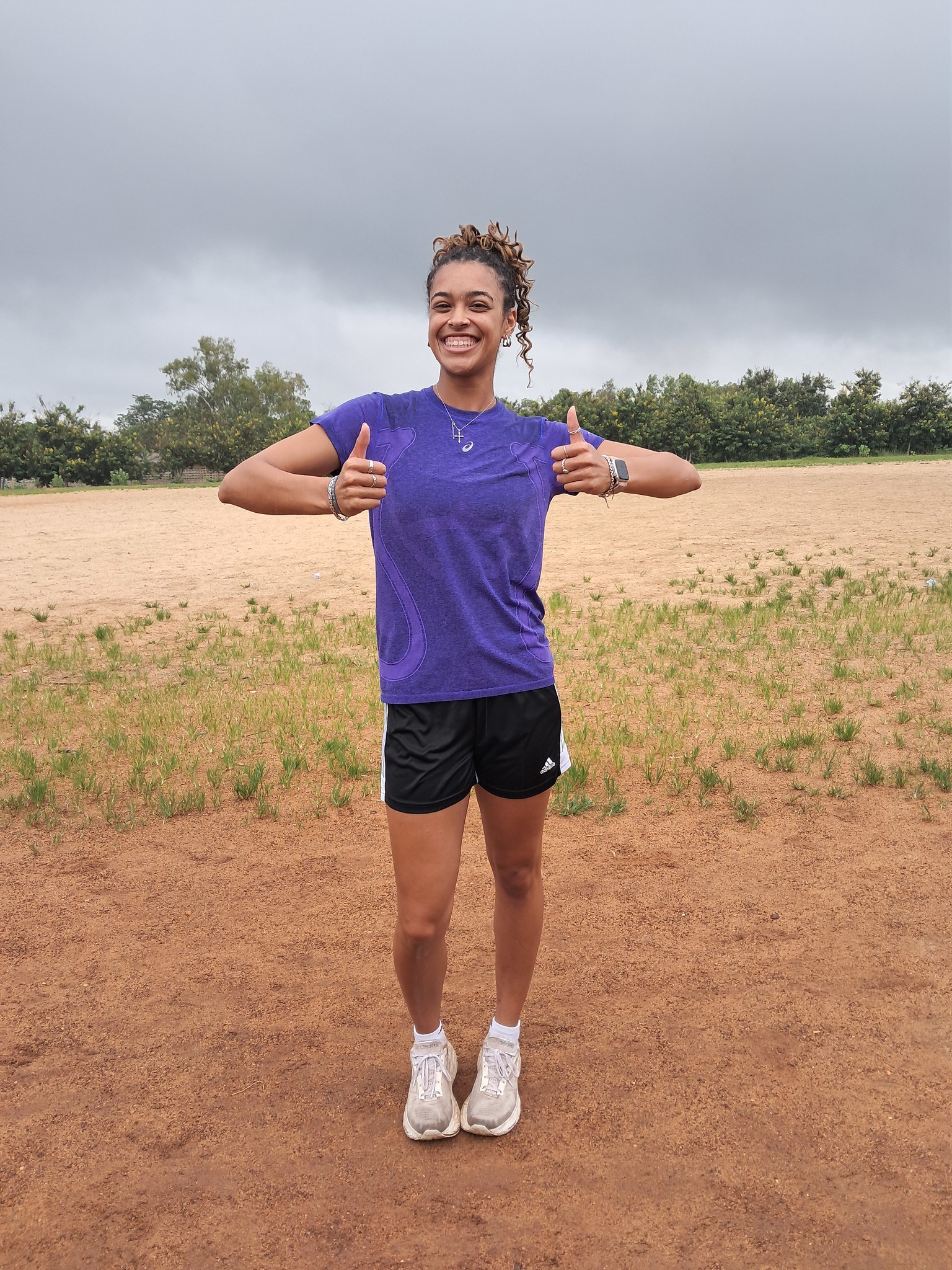 An AIA track athlete giving a thumbs up on the training field in Togo