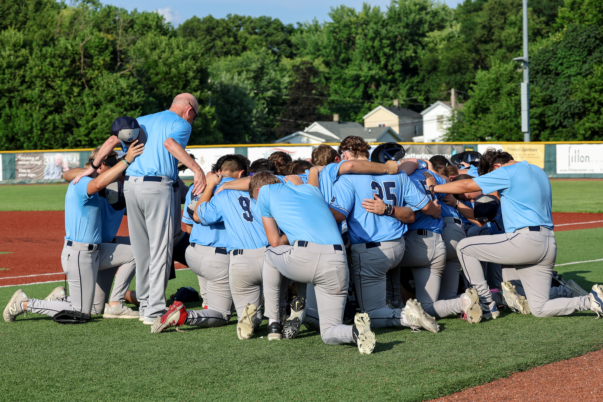 Xenia Scouts players kneeling together around their coach on the field