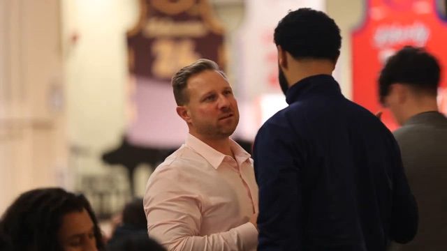 A college basketball coach in conversation with a player courtside at the AIA Total Athlete Tip-Off