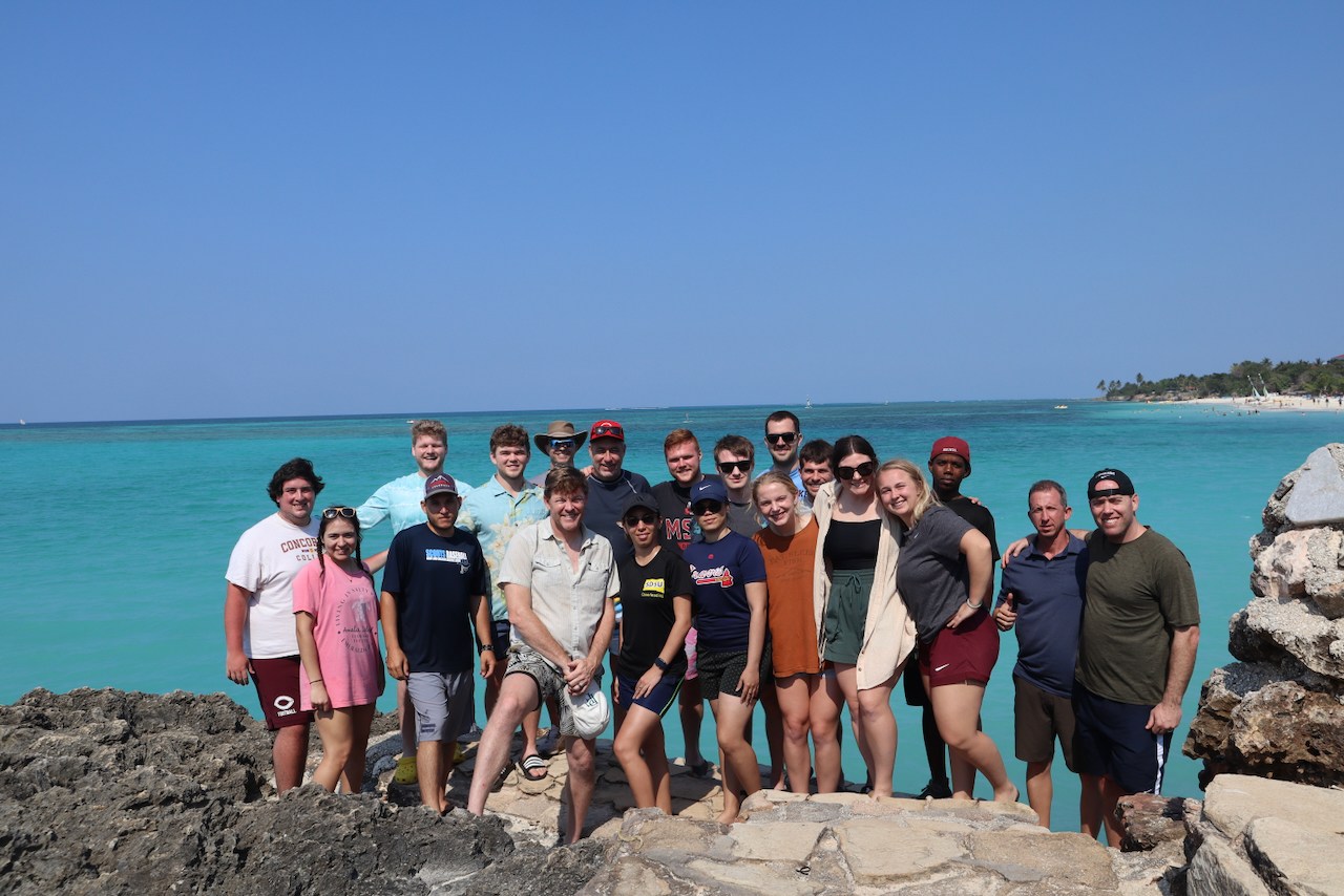 An AIA spring break team together on the beach in the Caribbean