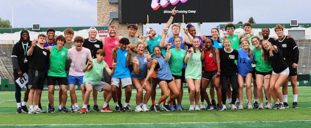 Indy college athletes and coaches celebrating together on a football field at Ultimate Training Camp