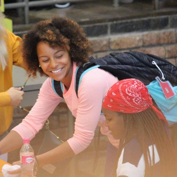 young woman wearing a backpack and smiling at a young girl