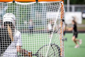 female lacrosse standing in front of net