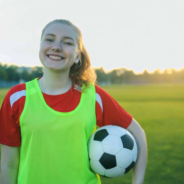 Female athlete smiling while holding a soccer ball
